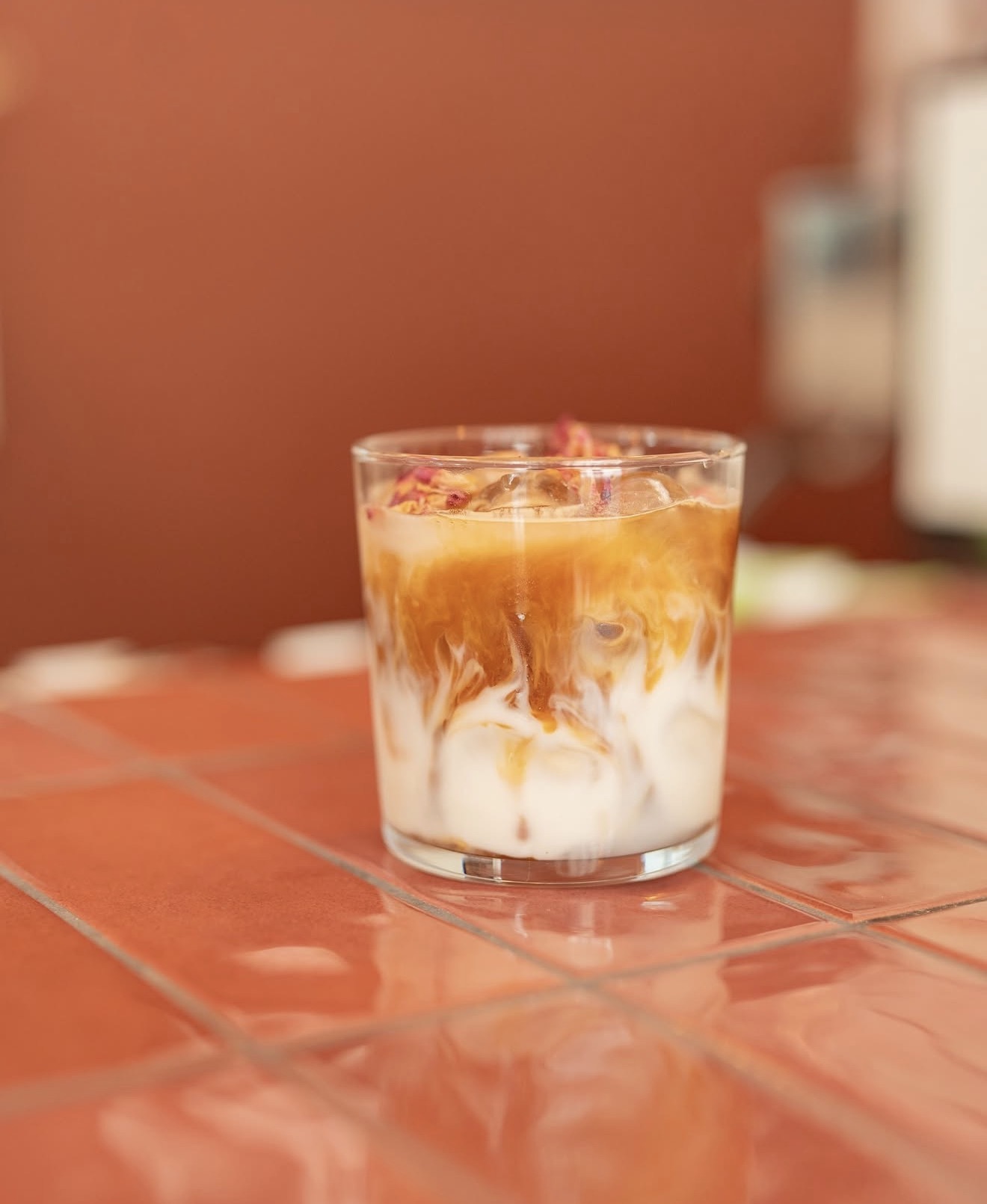 Iced latté aux pétales de rose sur carrelage terracotta