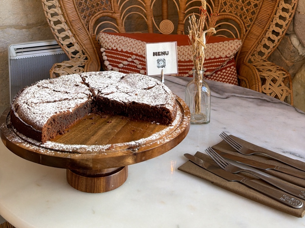 Gâteau au chocolat maison saupoudré de sucre glace sur présentoir bois chez Nessy Coffee